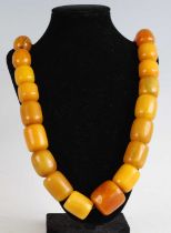 A beaded amber necklace, comprising eight butterscotch barrel beads and larger faux amber beads,