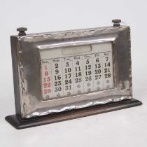 A George V silver clad perpetual desk calendar, with rolling apertures and on ebonised plinth, w.