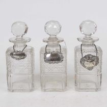 A set of three cut glass decanters and stoppers, each with silver decanter collar annotated for