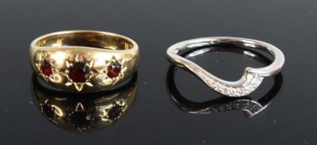 A modern 9ct gold garnet dress ring, the three graduated round cuts in gypsy settings, size O,