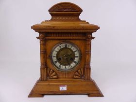 A late Victorian oak cased mantel clock, the brass dial having an enamel chapter ring with Roman