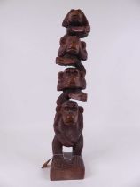 A carved hardwood totem in the form of four monkeys; hear no evil, see no evil, speak no evil,