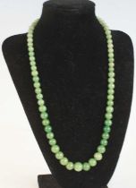 A single row of 71 graduated jadeite beads, strung plain to a yellow metal barrel clasp, bead