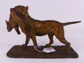 A painted spelter figure of a hound clutching a rabbit in its mouth, shown standing on a