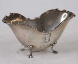 An early 20th century sterling silver sugar bowl, of boat shape, with cast scrolling rim, engraved