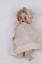 An early 20th century German bisque headed doll, having rolling glass eyes and two front teeth,