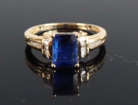 A modern 9ct gold sapphire and diamond dress ring, the four claw set emerald cut sapphire probably