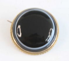A yellow metal banded agate target style brooch, featuring a cabochon cut agate within a ropetwist