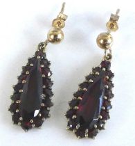 A pair of yellow metal garnet pear shaped cluster earrings, each featuring a centre pear cut