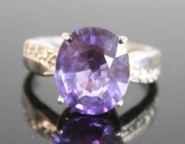 A white metal tanzanite dress ring, featuring an oval tanzanite in a four-claw setting, with four