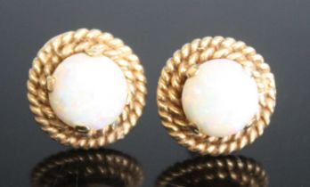 A pair of yellow metal opal circular stud earrings, each comprising a round opal cabochon claw set