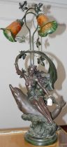 An Art Nouveau style bronzed composite twin branch table lamp, in the form of a lady seated on a