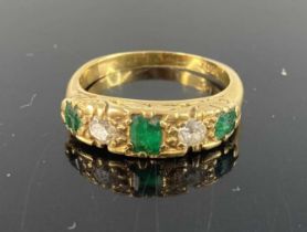 An 18ct gold emerald and diamond half hoop ring, the round cut stones in a carved line setting,