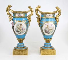A pair of late 19th century Servres style gilt bronze mounted porcelain urns of twin handled