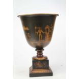 A reproduction toleware urn, gilt decorated with figures, mounted upon a square plinth, height 31cm