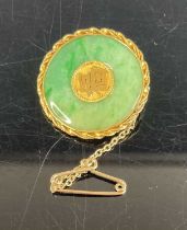 A Chinese yellow metal and jade disc brooch, the centre set with a Chinese symbol, with safety