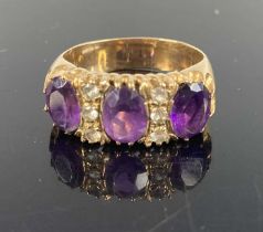 A heavy 9ct gold amethyst three stone ring, the oval cut amethyst each dispersed with three small