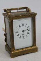 An early 20th century lacquered brass carriage clock, the enamel dial showing Roman numerals, having
