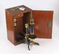 An early 20th century lacquered brass and iron monocular microscope having a rack and pinion