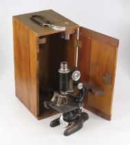 A 20th century iron monocular microscope having a three optic turret above a sliding scale platform,