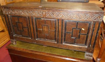 An 18th century oak three-panelled hinge top coffer, having later blind carved frieze and associated