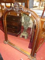 A Victorian style heavily floral carved oak arched over mantel mirror, having scallop shell