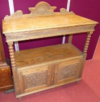 An early 20th century floral relief carved oak ledge back two-tier buffet, having bobbin turned