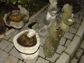 A collection of various composite and concrete garden effects to include birdbaths, recumbent dog,
