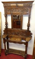 A circa 1900 heavily relief carved oak mirror back hall stand, having hinged central compartment,