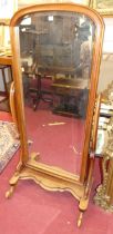 A Victorian style hard wood arched bevelled cheval mirror raised on scroll stand, the mirror 146.5 x