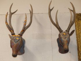 A pair of decorative carved and painted polychrome stags heads, each wall mounted with antlers (each