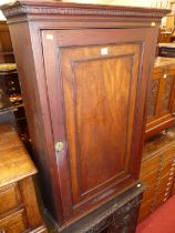 An early 19th century mahogany single door hanging corner cupboard