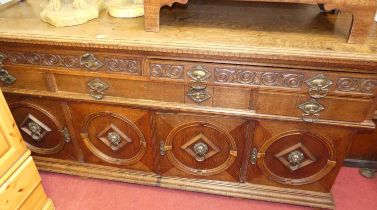 An early 20th century geometric and relief carved oak sideboard in the Jacobean taste, having an