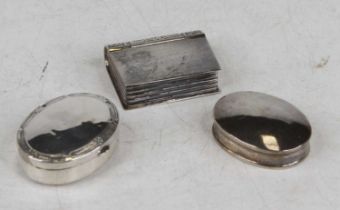 A modern white metal pill box in the form of a book, 3.5cm, together with two oval examples, one