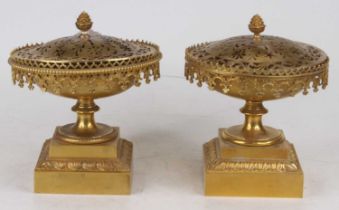 A pair of brass censers, each having pierced lid surmounted by a pinecone finial, on circular