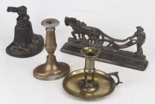 A black painted cast iron door stop in the form of a bell, together with a brass candlestick in