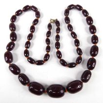 A cherry amber necklace, arranged as 49 graduated barrel beads on a knotted string, the largest bead