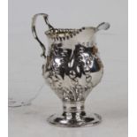 A George II silver and embossed pedestal cream jug, of helmet form, 2.8oz, London 1759, h.9.5cm