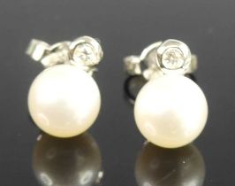 A pair of white metal pearl and diamond stud earrings, each featuring a 6.9mm Akoya cultured pearl