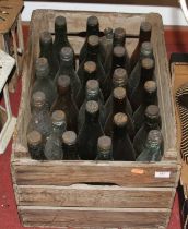 A vintage wooden crate containing glass bottles, mainly local examples No paper labels present,