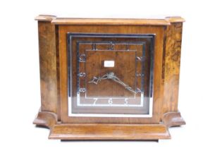 An Art Deco walnut and burr walnut cased mantel clock, having a silvered square Arabic chapter ring,