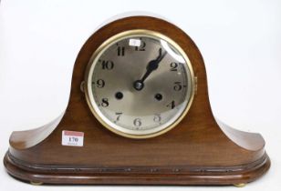 A circa 1920 walnut cased "Napoleon hat" mantel clock, having a signed silvered Arabic dial, and