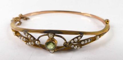 An Edwardian 9ct gold green peridot and seed pearl set hinged bangle, 6.6g, 68mm, in fitted