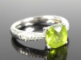 A contemporary 18ct white gold peridot and diamond dress ring, arranged as a four claw set cushion