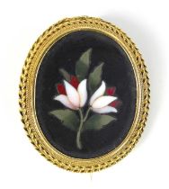 A yellow metal oval pietra dura brooch depicting stylised lilies within a ropetwist mount, brooch