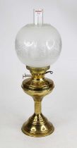 A brass oil lamp, having an etched glass shade, height 55cm