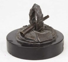A bronzed WW2 metal desk weight, in the form of a telescope and wreath, mounted to a black