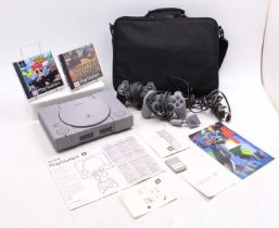 A Sony Playstation One housed in a soft case bag with 2 controllers, the original instruction