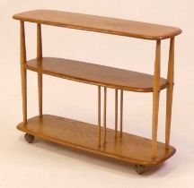 A 1960s Ercol blond elm Windsor 361 'Baby Giraffe' three-tier bookcase trolley, with divisional