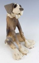A contemporary studio pottery model of a seated dog, painted in tones of brown and cream, with